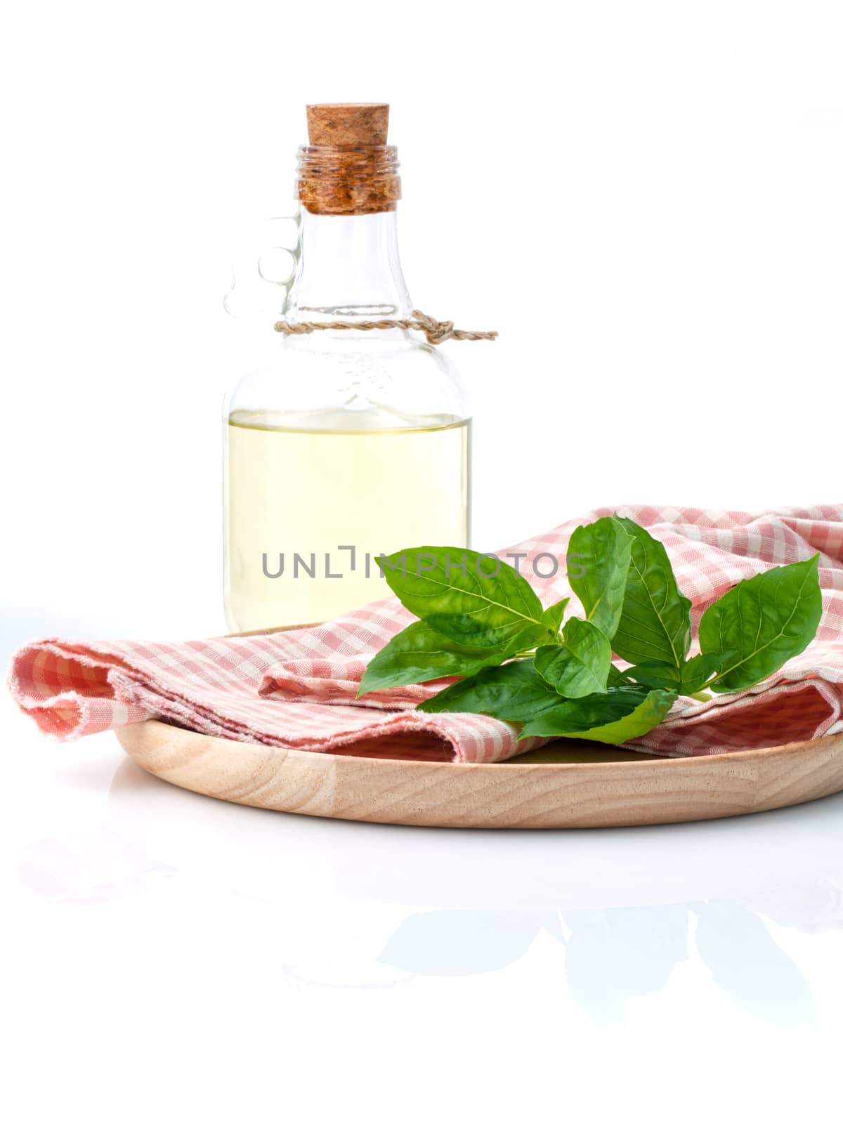 Branch of fresh  basil in wooden plate with olive oil on cutting board isolate on white background.