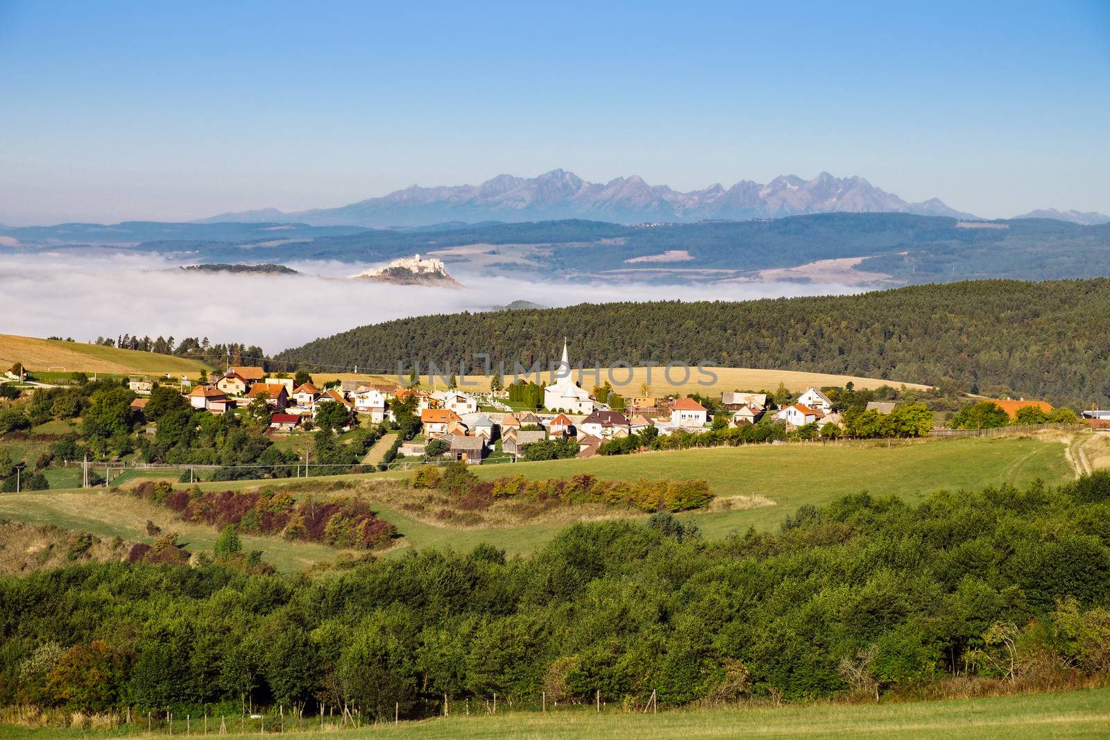 Scenic view of traditional village, Spis castle, meadows and High Tatras mountain range, Slovakia