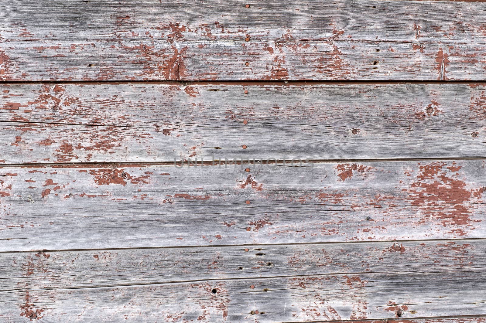 The red paint that once covered these planks is now faded and peeled.