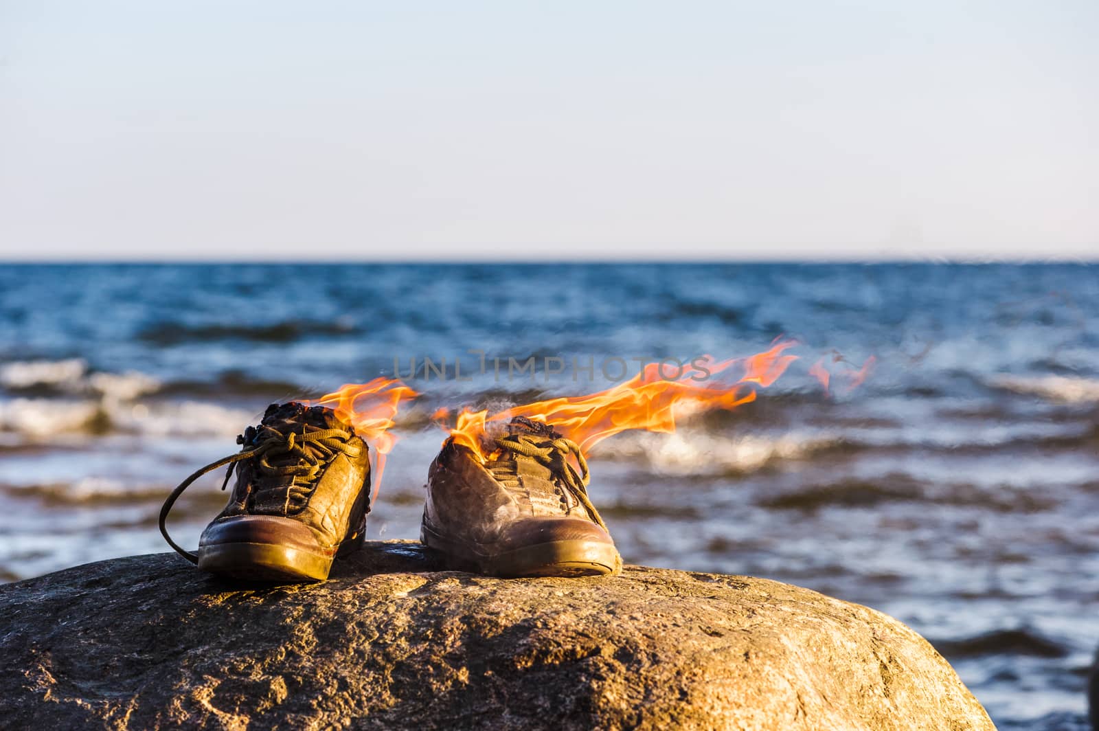 Sneakers in fire flames on the seashore