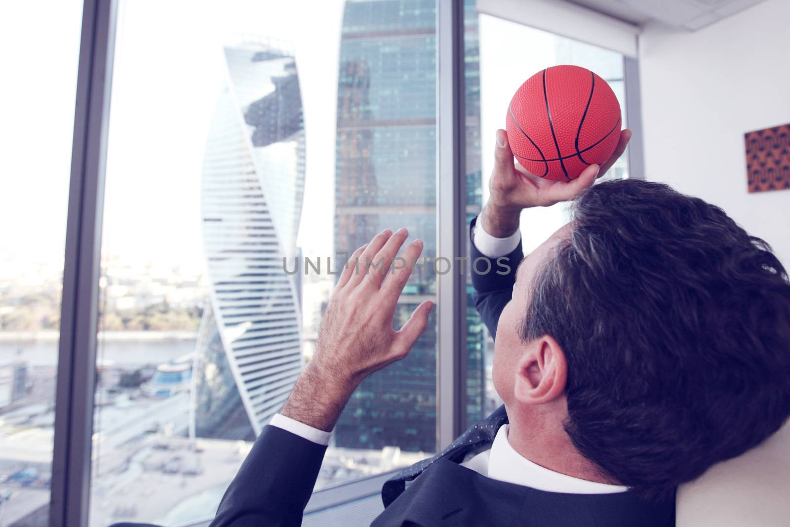 Business man playing with a basketball at the office