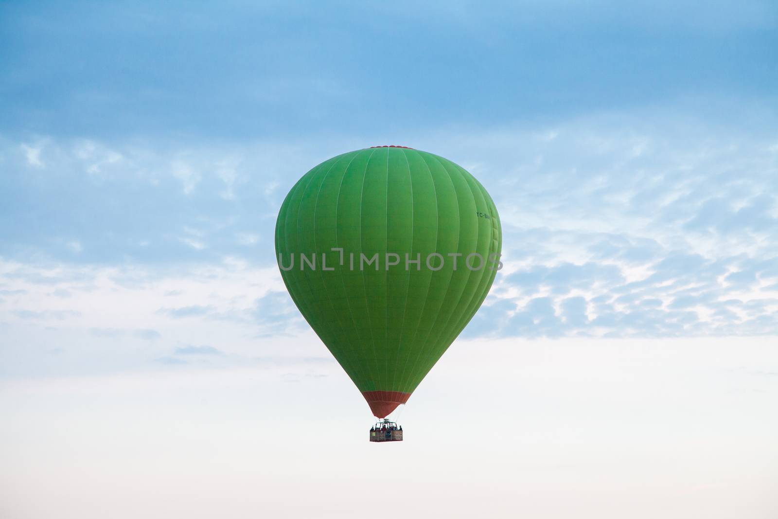 Green hot air balloon travelling up in the air by haiderazim