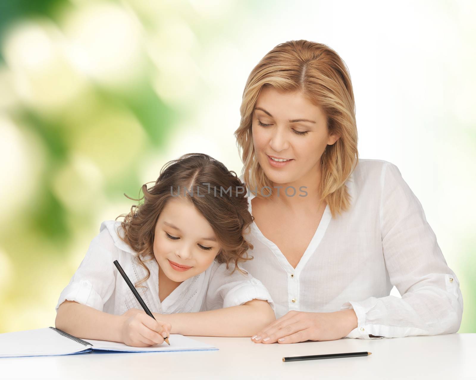 happy mother and daughter writing in notebook by dolgachov