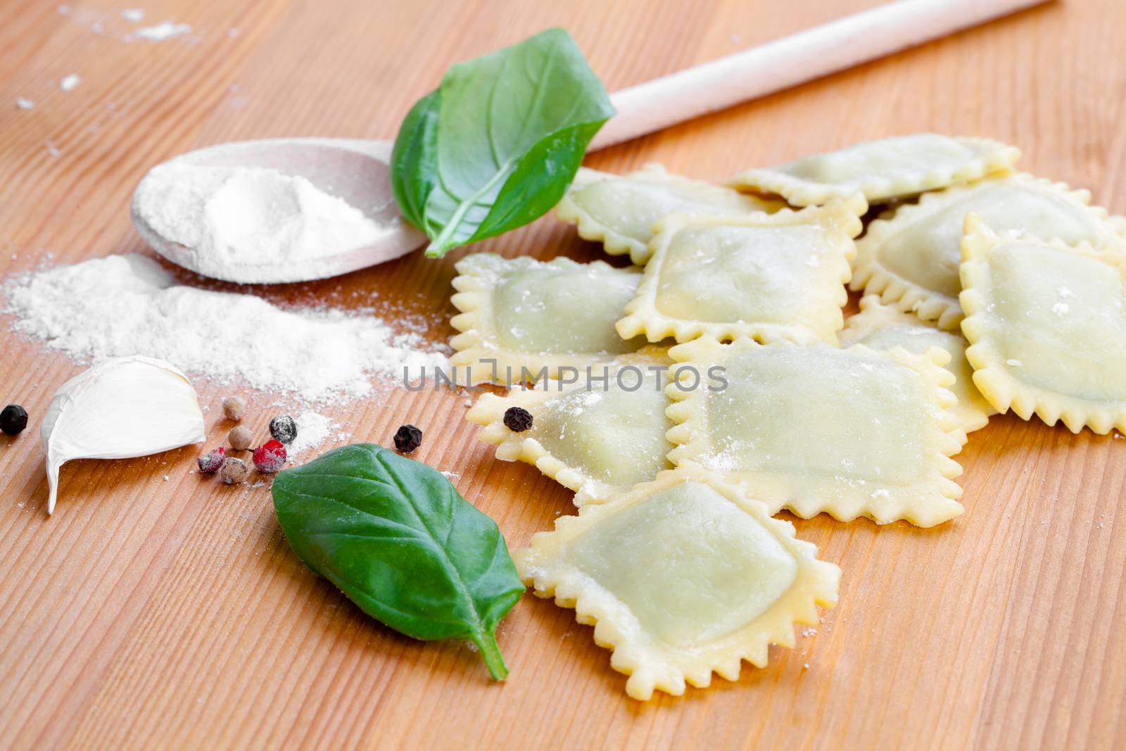 Raw ravioli with flour on wooden table