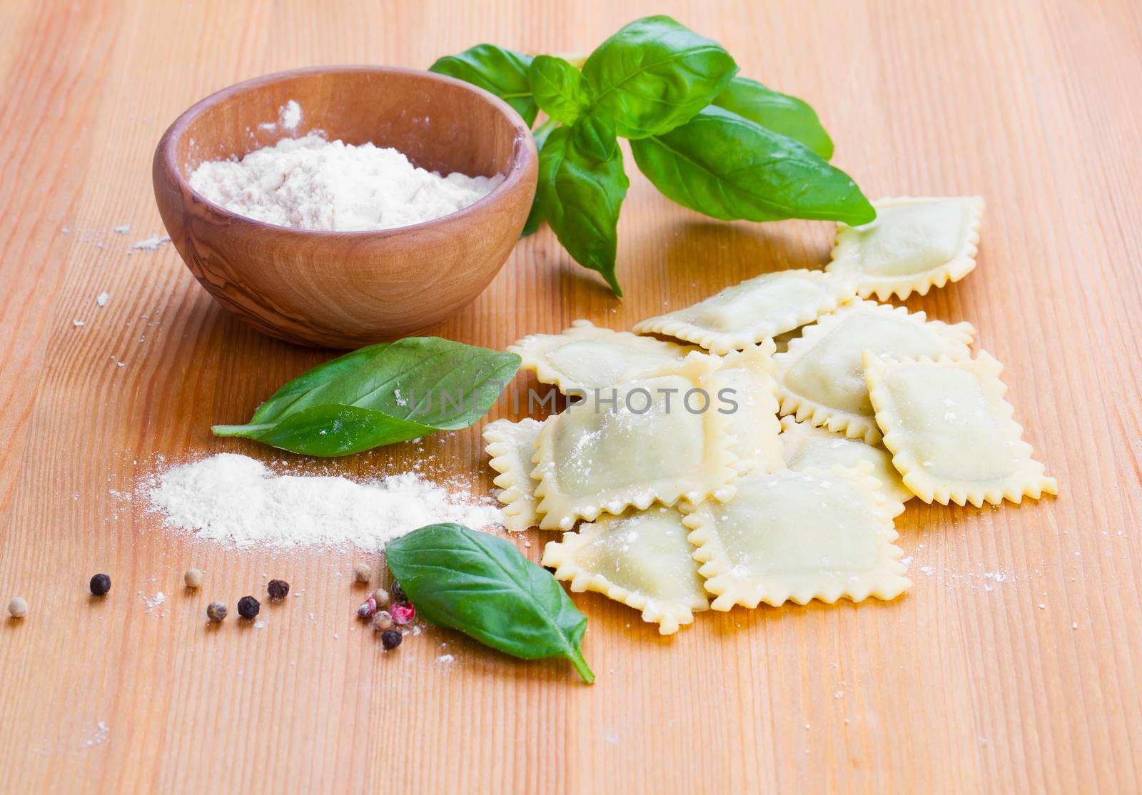 Raw ravioli with flour on wooden table