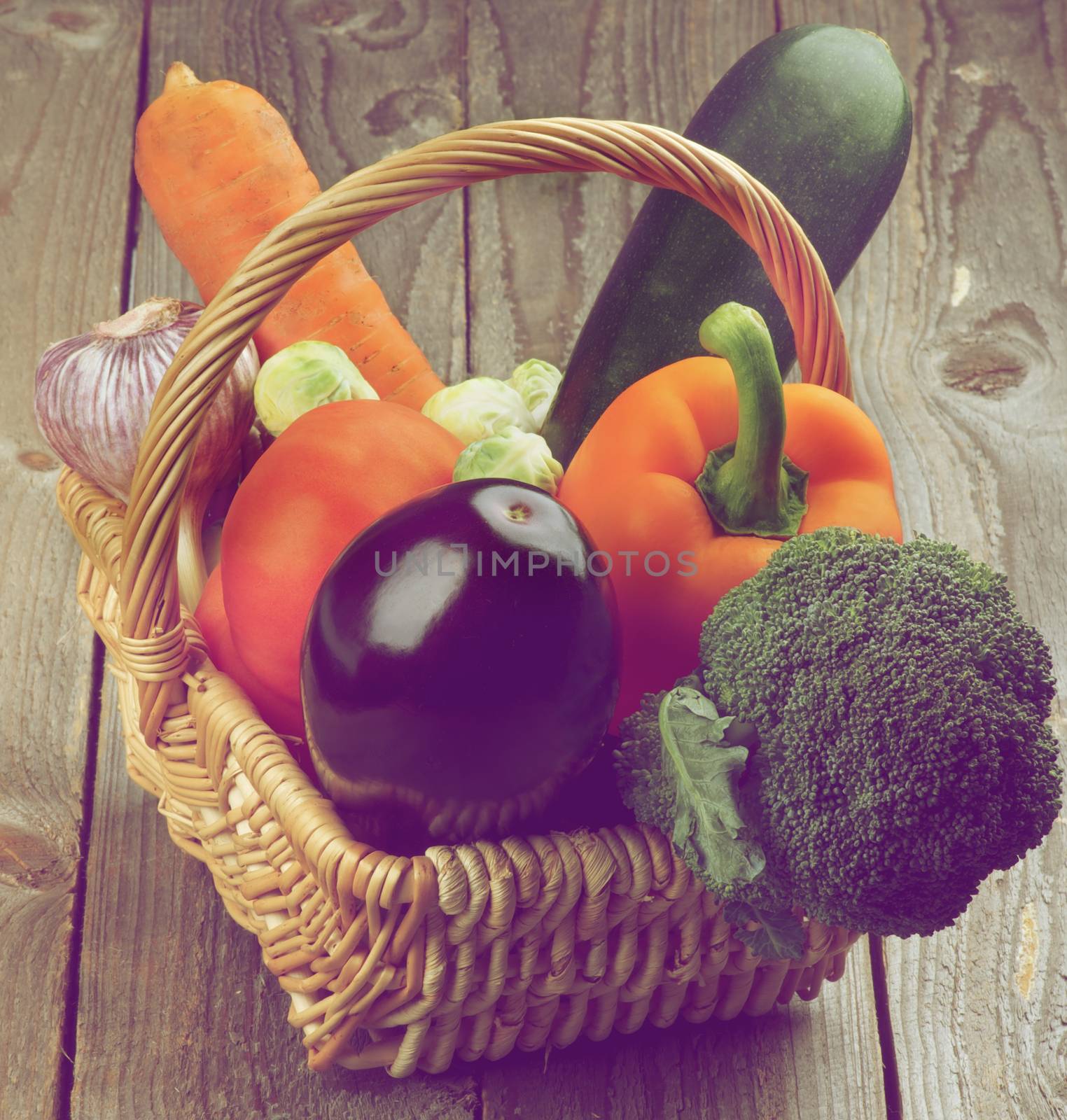 Various Colorful Ripe Raw Vegetables in Wicker Basket closeup on Rustic Wooden background. Retro Styled