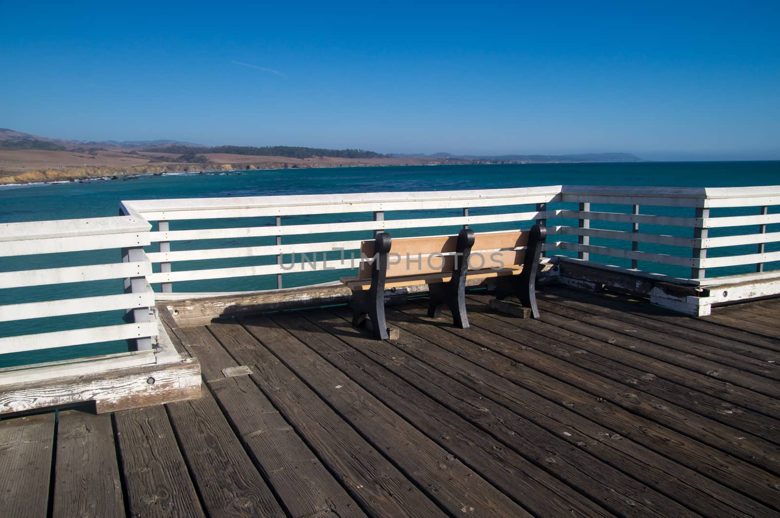 Bench on pier overlooks California coastline