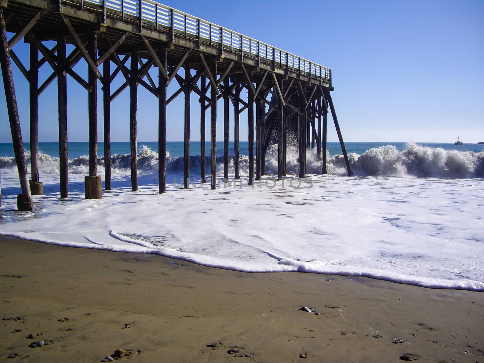 Waves pound the wooden pier in California by emattil