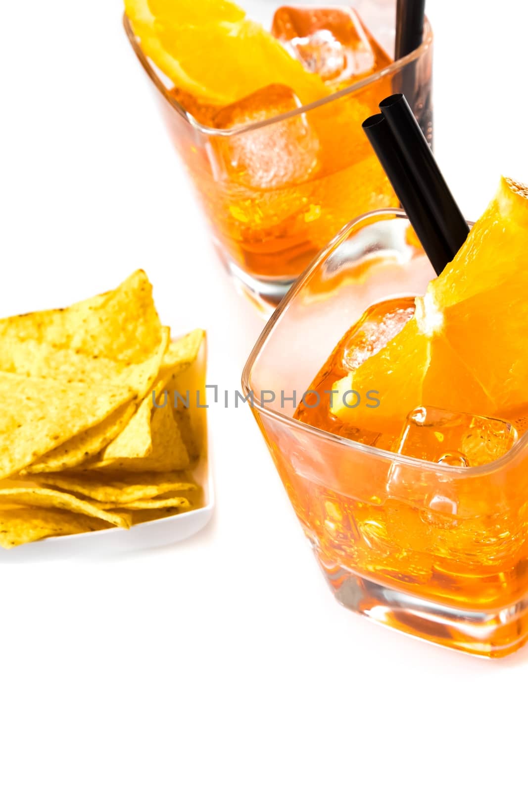 top of view of hot tacos chips in front of two glasses of spritz aperitif aperol cocktail with orange slices and ice cubes on white background