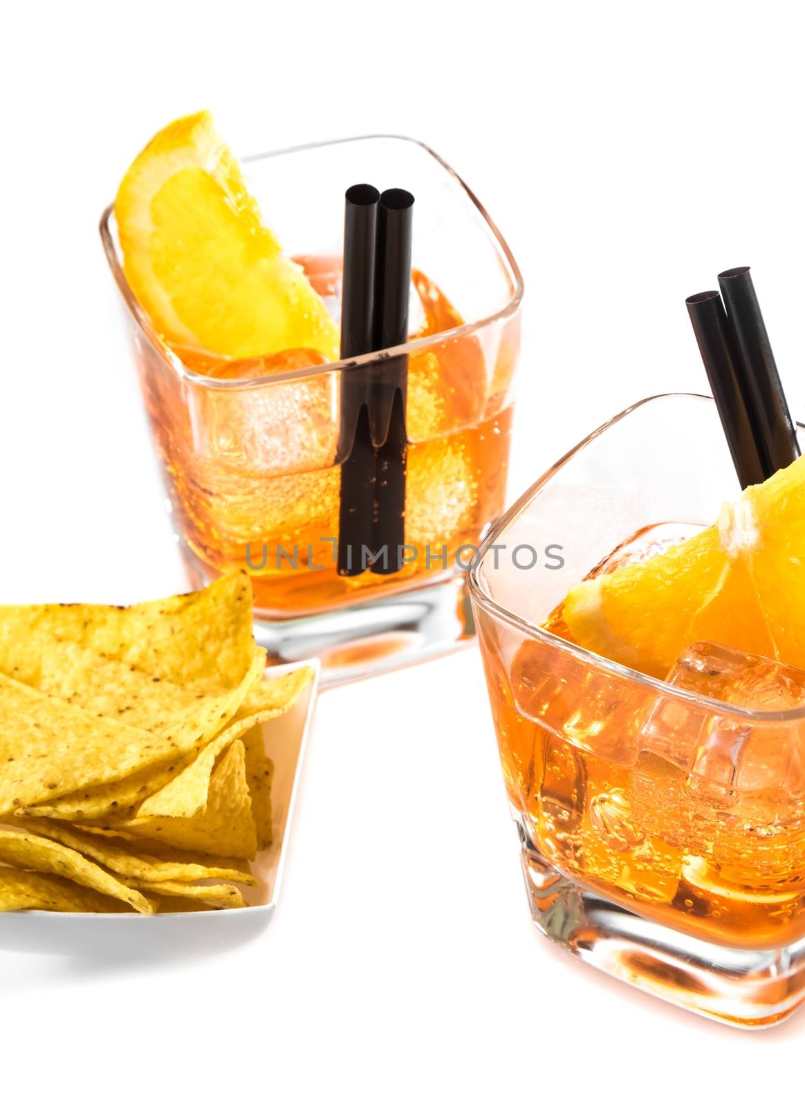 top of view of two glasses of spritz aperitif aperol cocktail with orange slices and ice cubes near tacos chips on white background