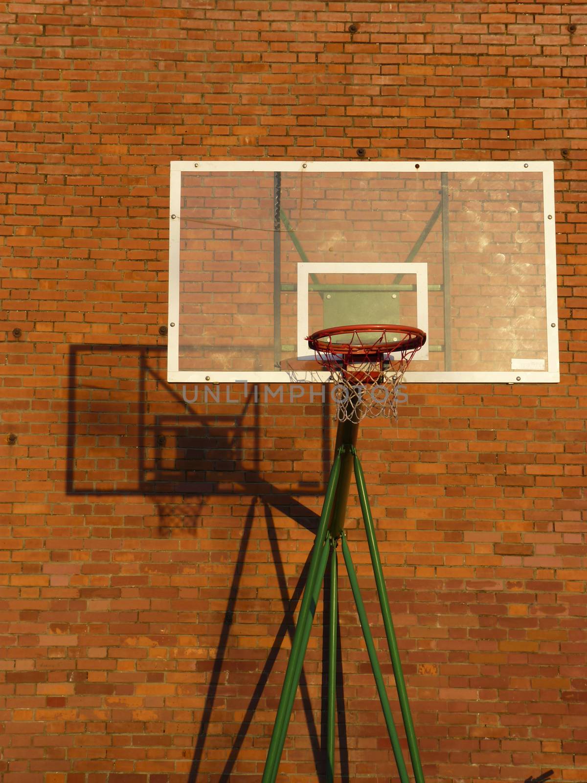 Basketball backboard and net with his shadow on the red wall of bricks