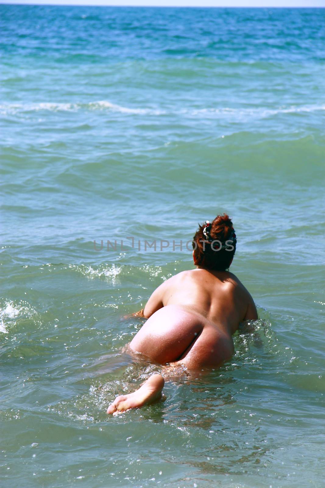 Sexy naked young woman entering the water