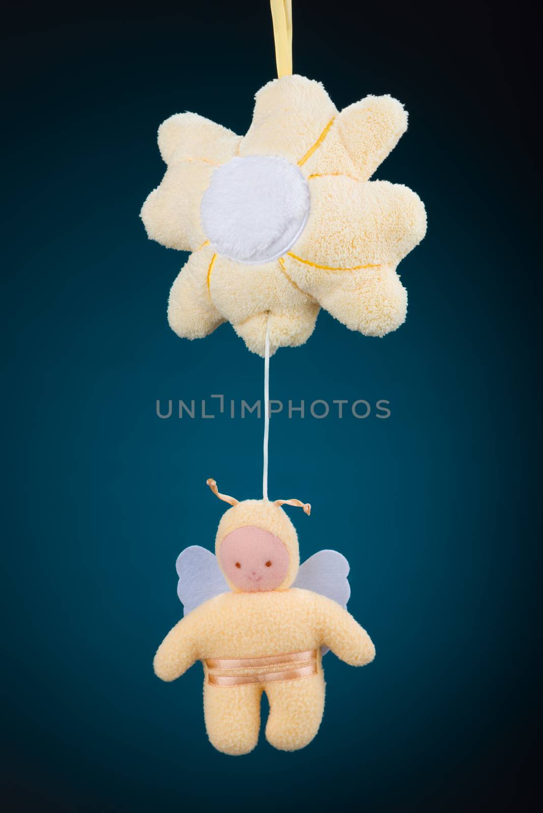 A yellow flower and bumblebee baby mobile on a blue background with a natural black vignette.