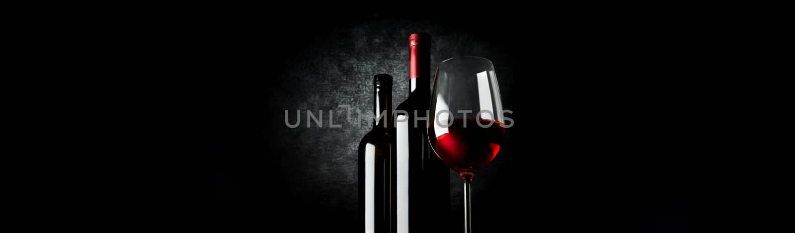 Two bottles and wineglass on a black background