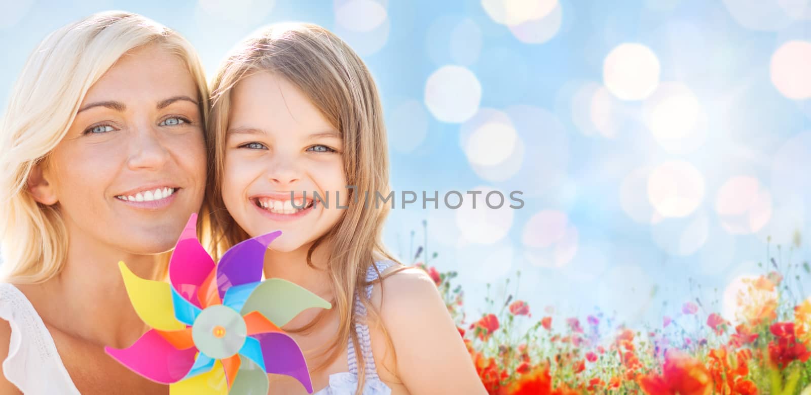 summer holidays, family, children and people concept - happy mother and girl with pinwheel toy over blue lights and poppy field background