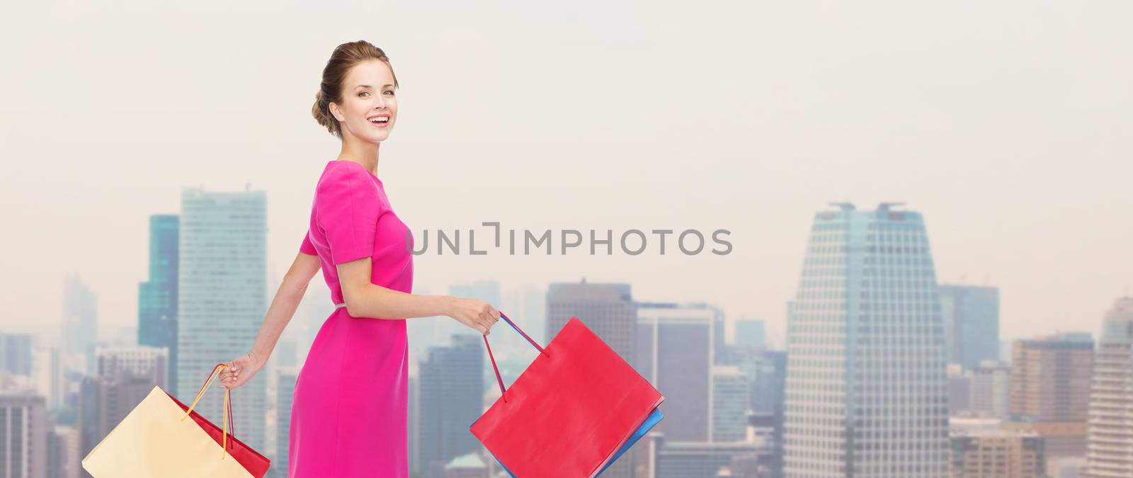 young happy woman with shopping bags over city by dolgachov