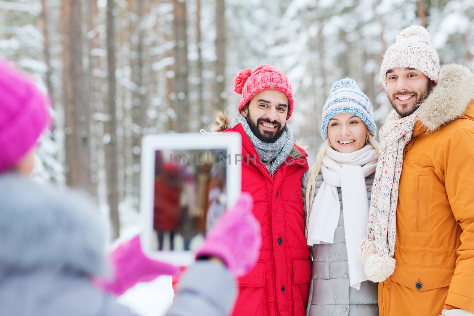 smiling friends with tablet pc in winter forest by dolgachov