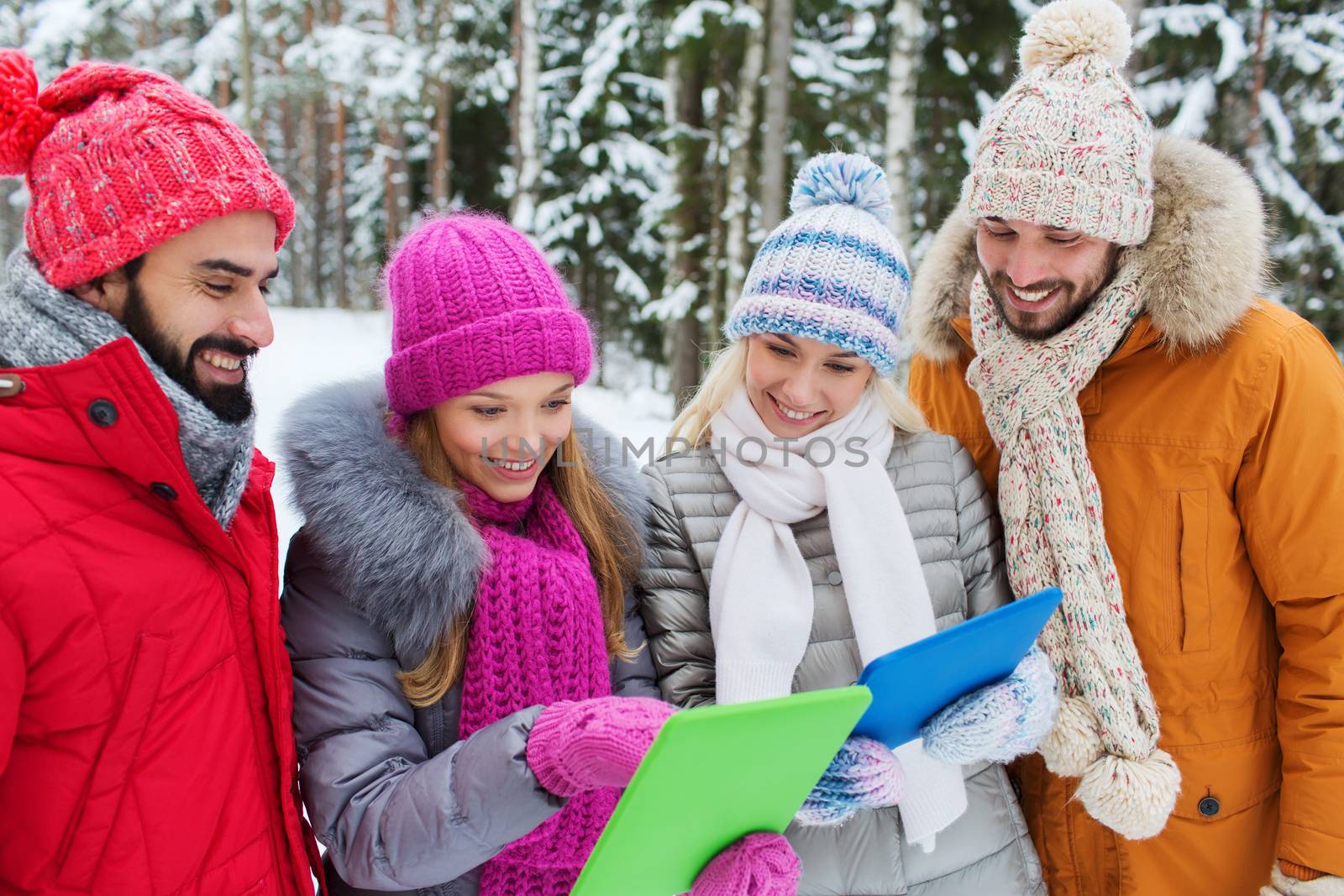 technology, season, friendship and people concept - group of smiling men and women with tablet pc computers in winter forest