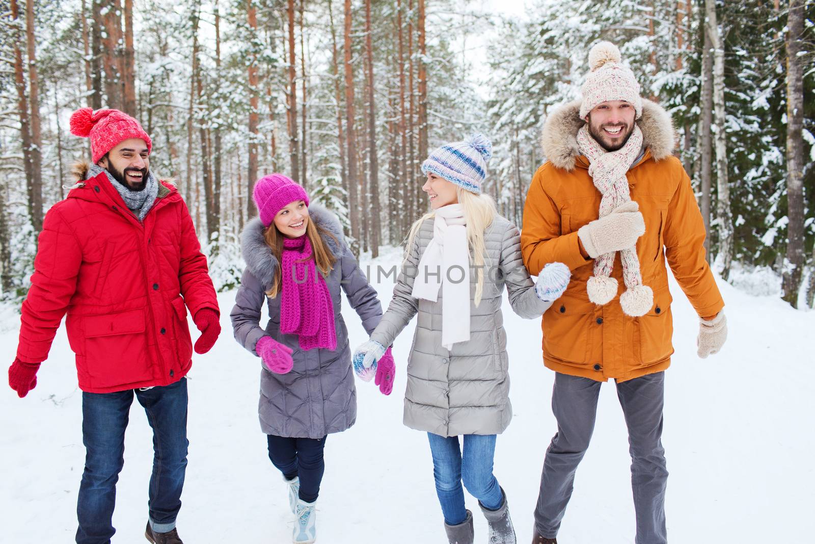 group of smiling men and women in winter forest by dolgachov