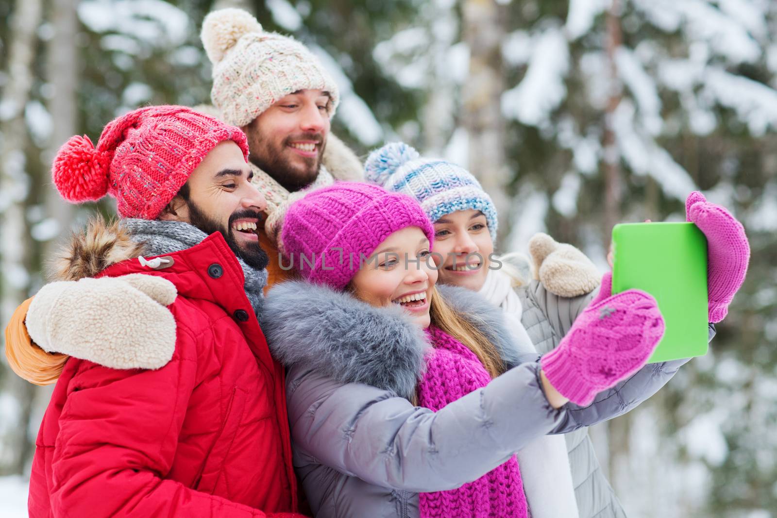 technology, season, friendship and people concept - group of smiling men and women taking selfie tablet pc computer in winter forest