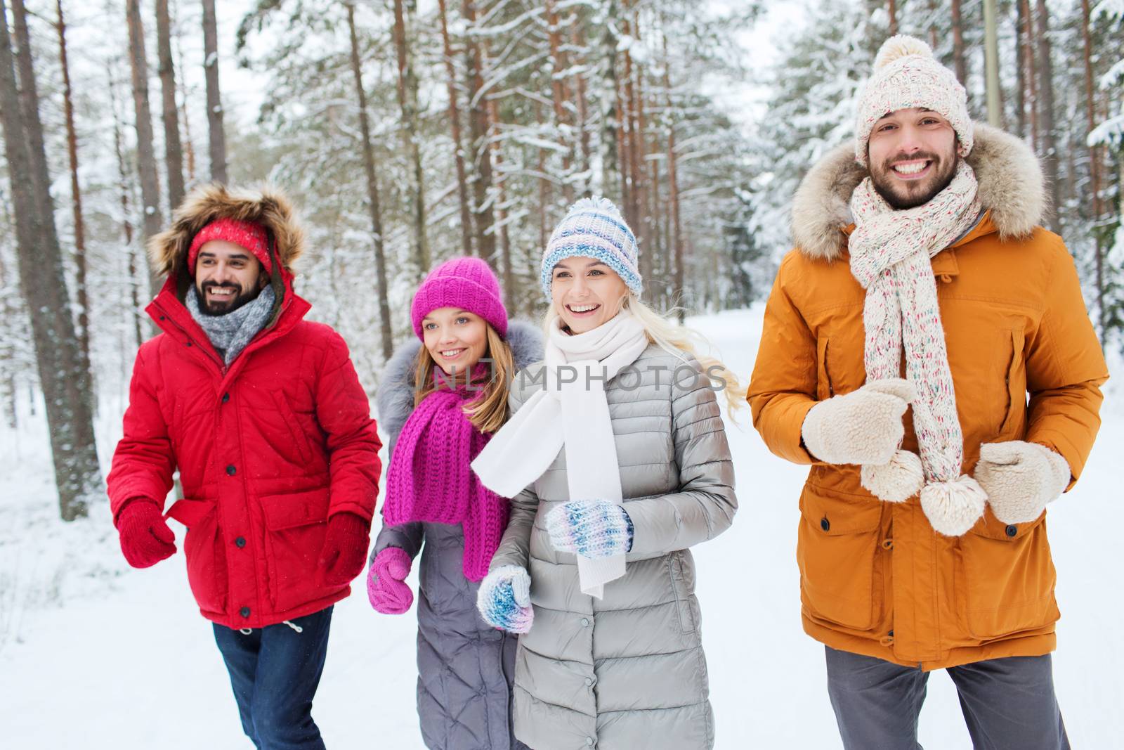 group of smiling men and women in winter forest by dolgachov