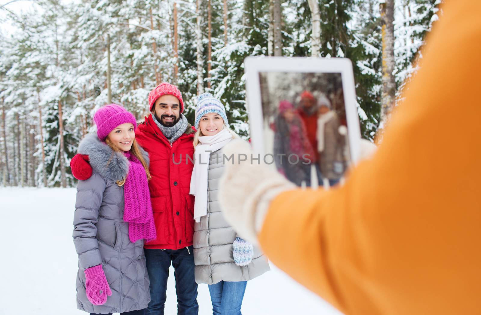smiling friends with tablet pc in winter forest by dolgachov