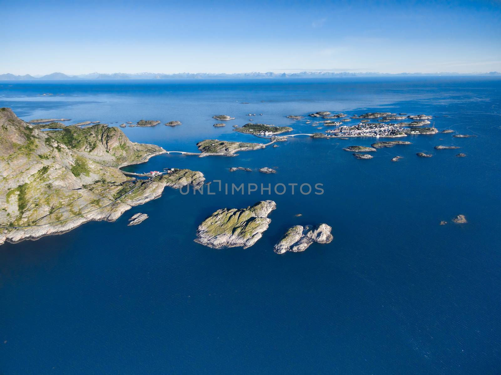 Aerial view of picturesque fishing port Henningsvaer on small islands in the sea and road bridges leading to it