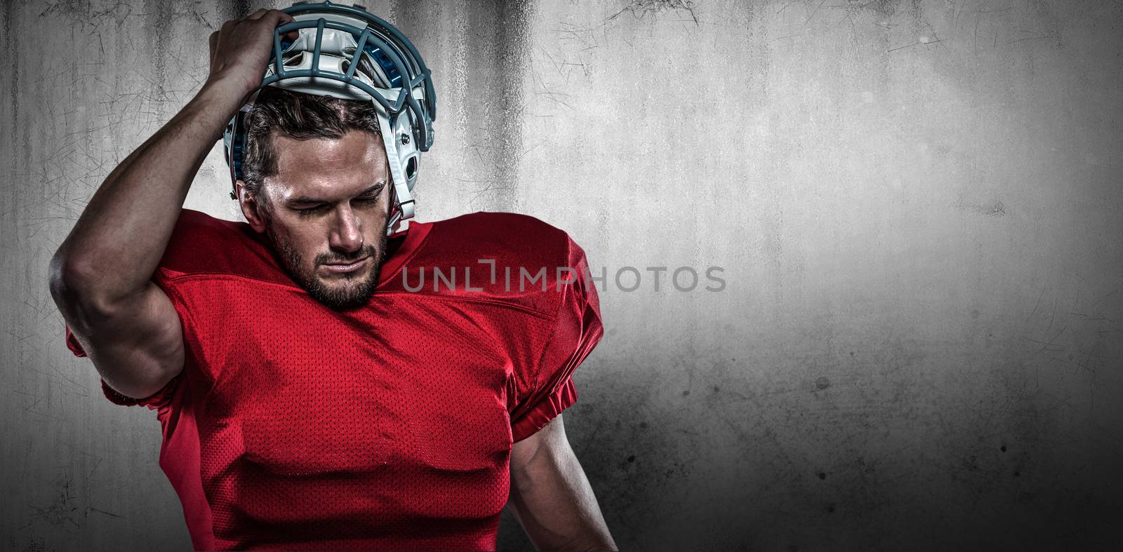 American football player in removing helmet against grey background