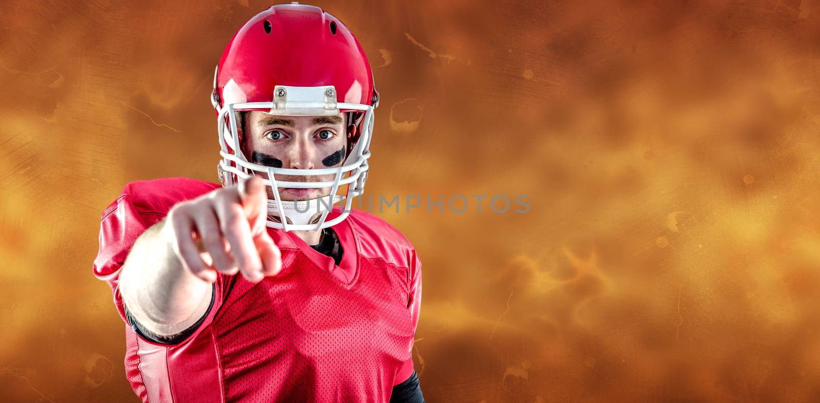 Portrait of american football player pointing to camera against orange background