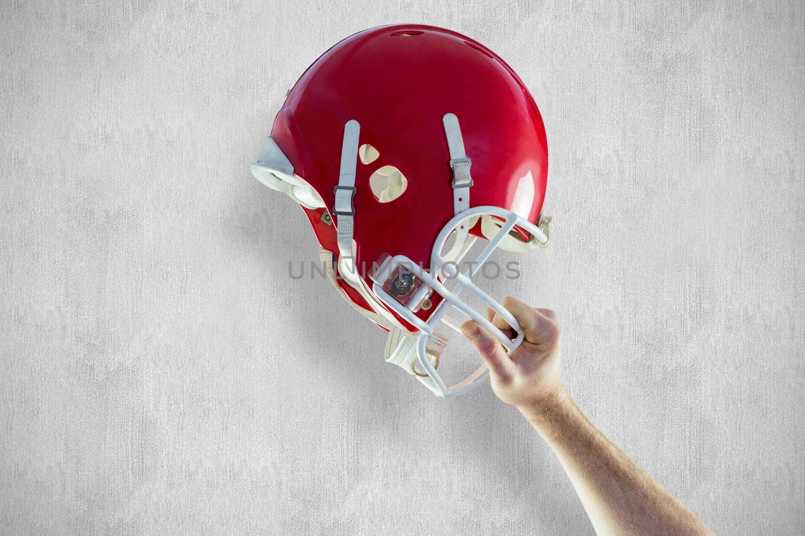 American football player holding up his helmet against white and grey background