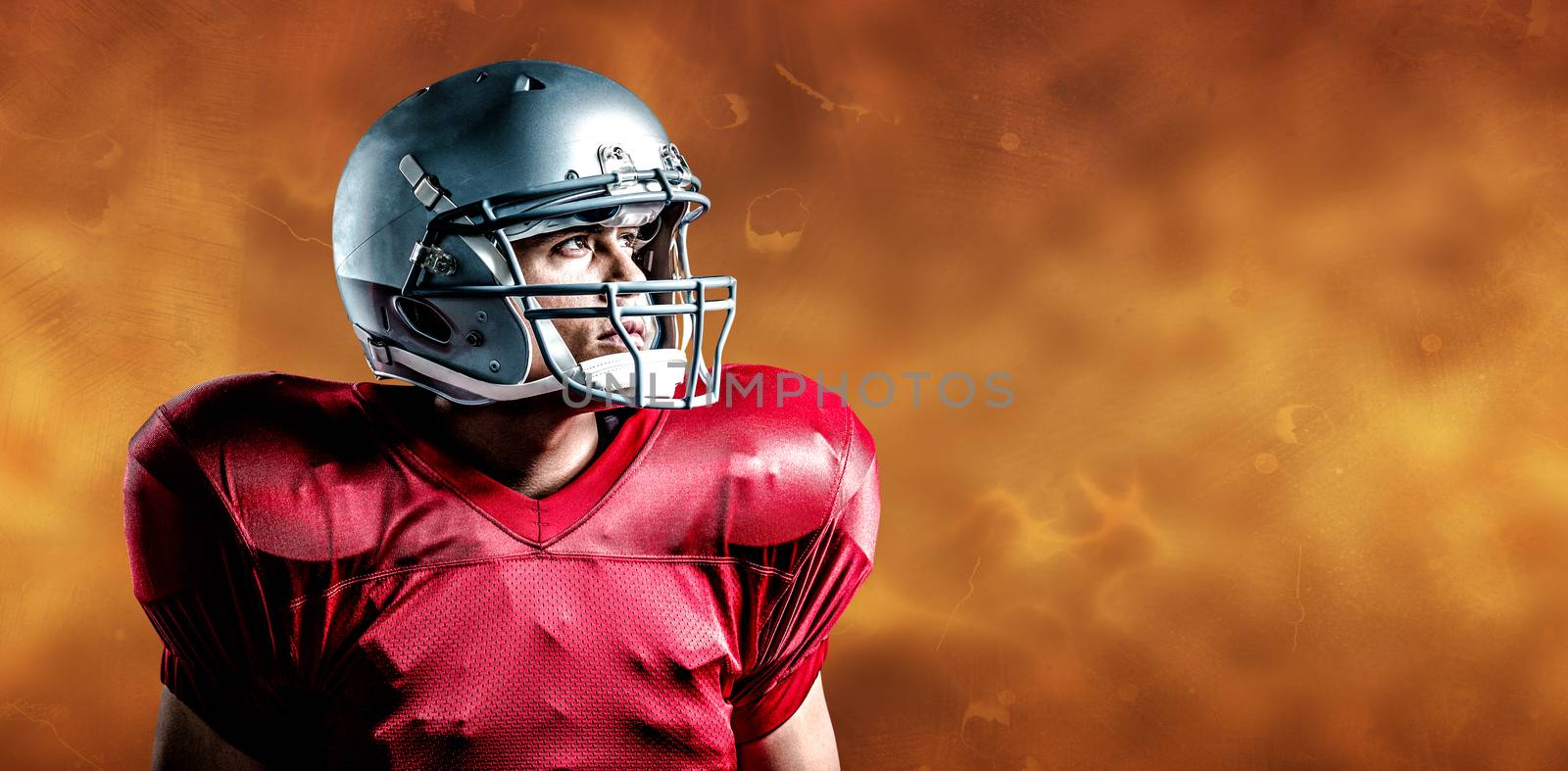 American football player looking away while standing against orange background