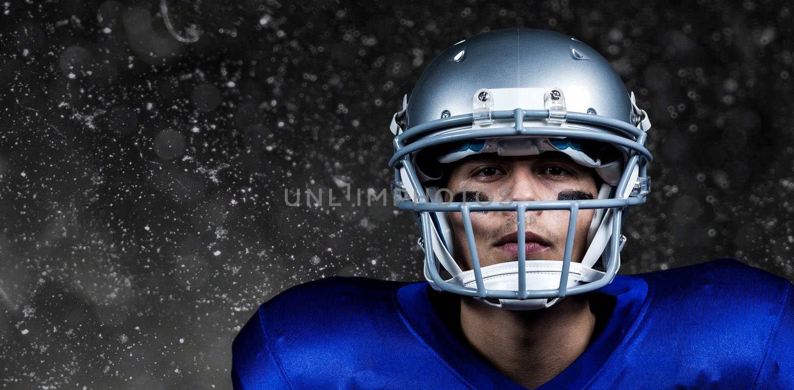 Portrait of determined American football player in uniform against black background