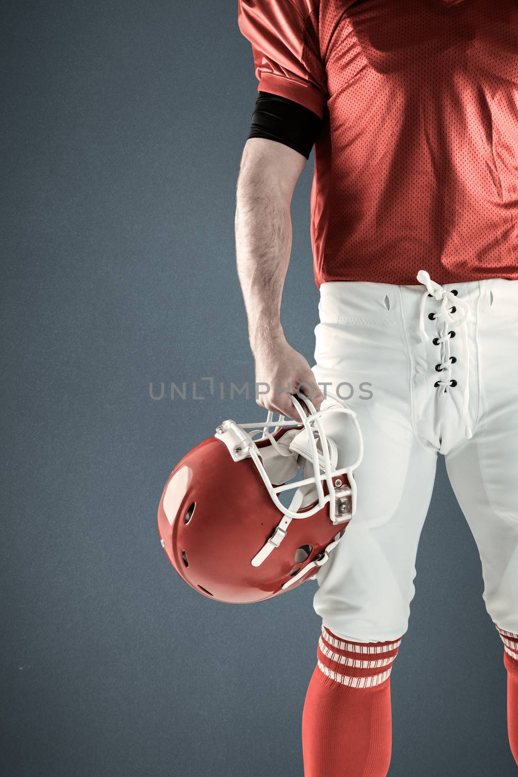 Composite image of front view of american football player holding his helmet by Wavebreakmedia