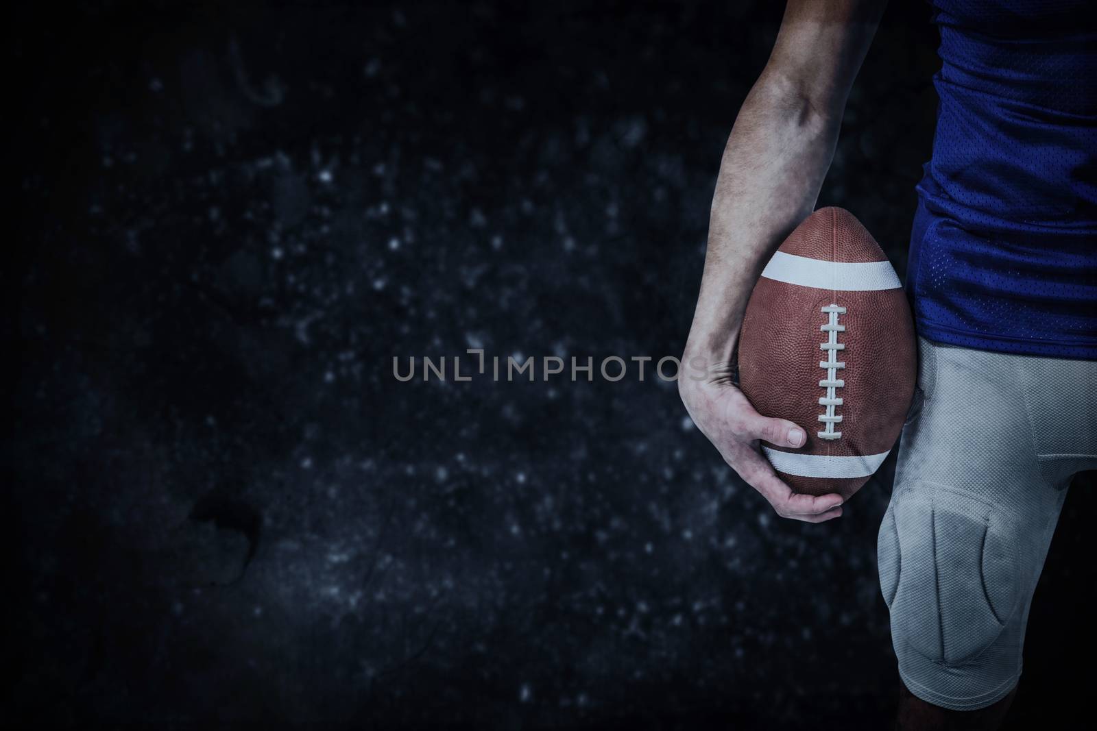 Sports player holding ball against black background