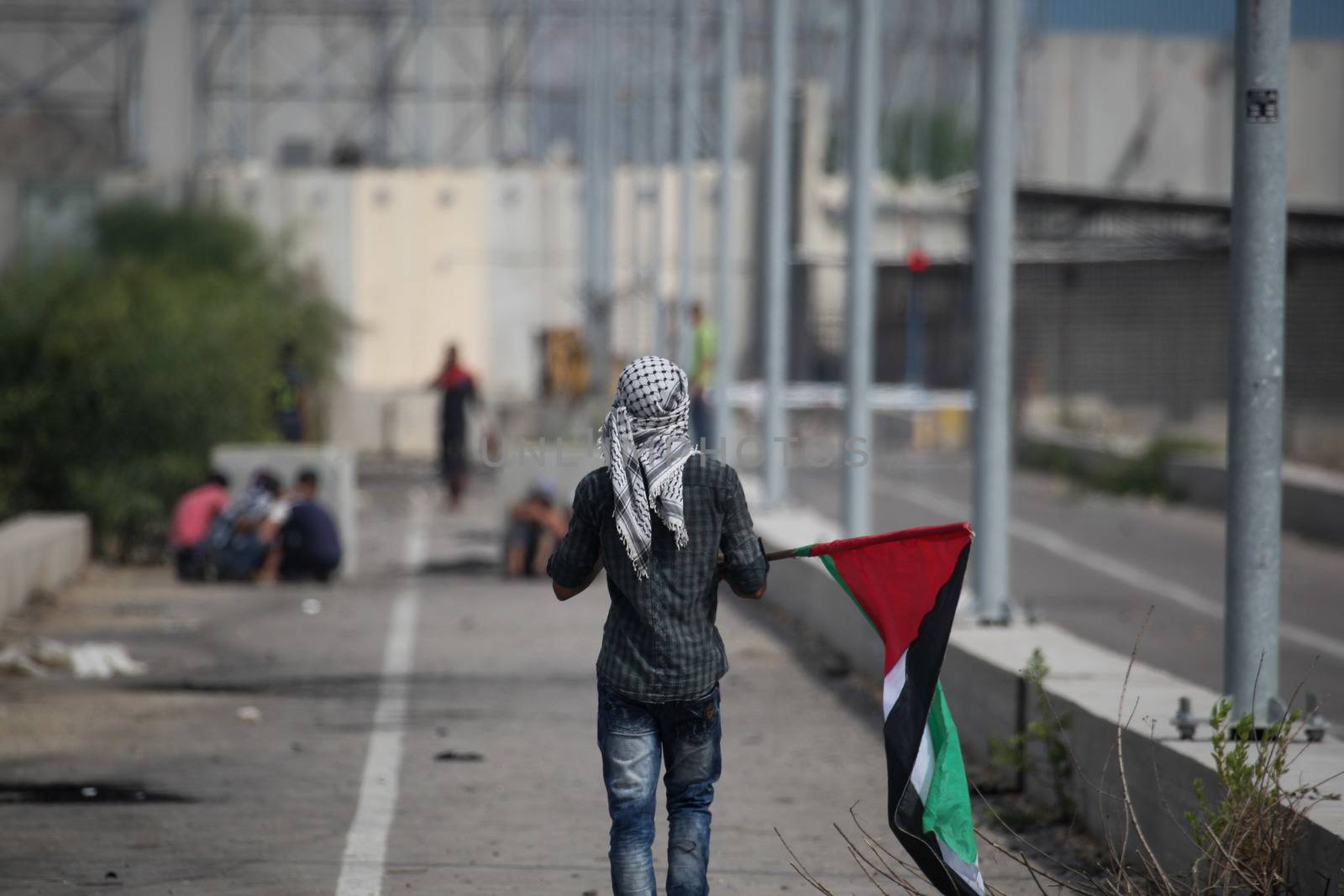 PALESTINE, Gaza Strip: A young man holds a Palestinian flag as protesters battled with Israeli security forces near the Erez crossing between Israel and the Gaza Strip on October 13, 2015.As a wave of stabbings hit Jerusalem, violent protests flared up in the West Bank. The unrest has lead to warnings that a full-scale Palestinian uprising, or Intifada, could erupt. The unrest has also spread to the Gaza Strip, with fighting along the border in recent days leaving nine Palestinians dead. 