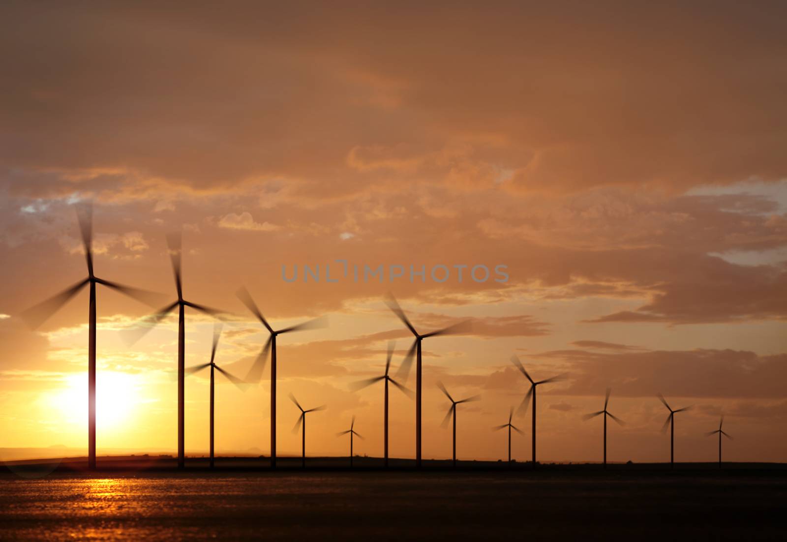 silhouette of wind turbine generating electricity on sunset