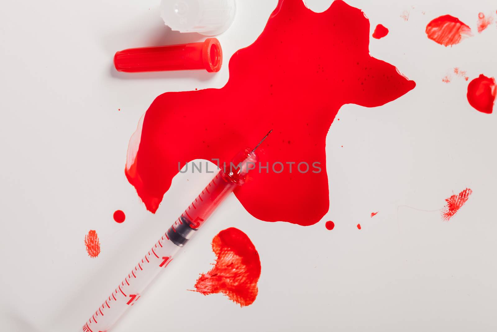 High Angle View of Syringe Needle Squirting Red Liquid or Blood onto White Background in Studio Still Life - Concept Image