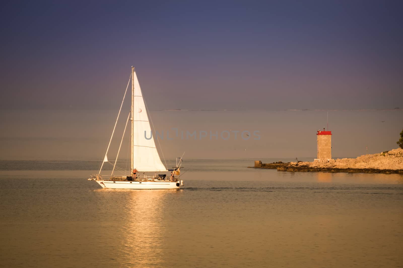 RAB, CROATIA - CIRCA AUGUST 2015: Sailing boat takes off in the early morning golden light.