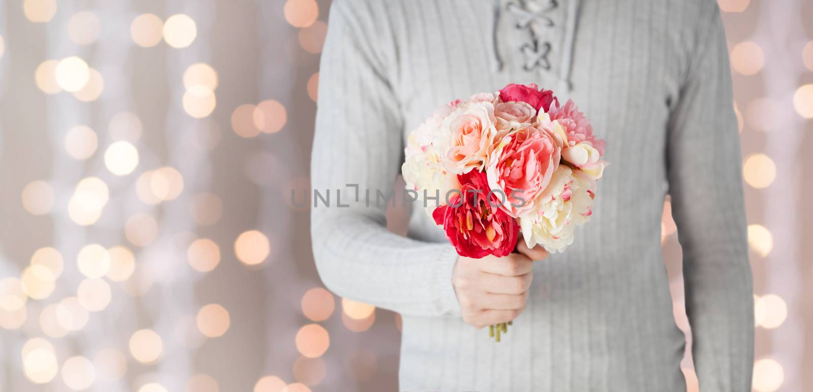 holidays, people, feelings and greetings concept - close up of man holding bunch of flowers over lights background