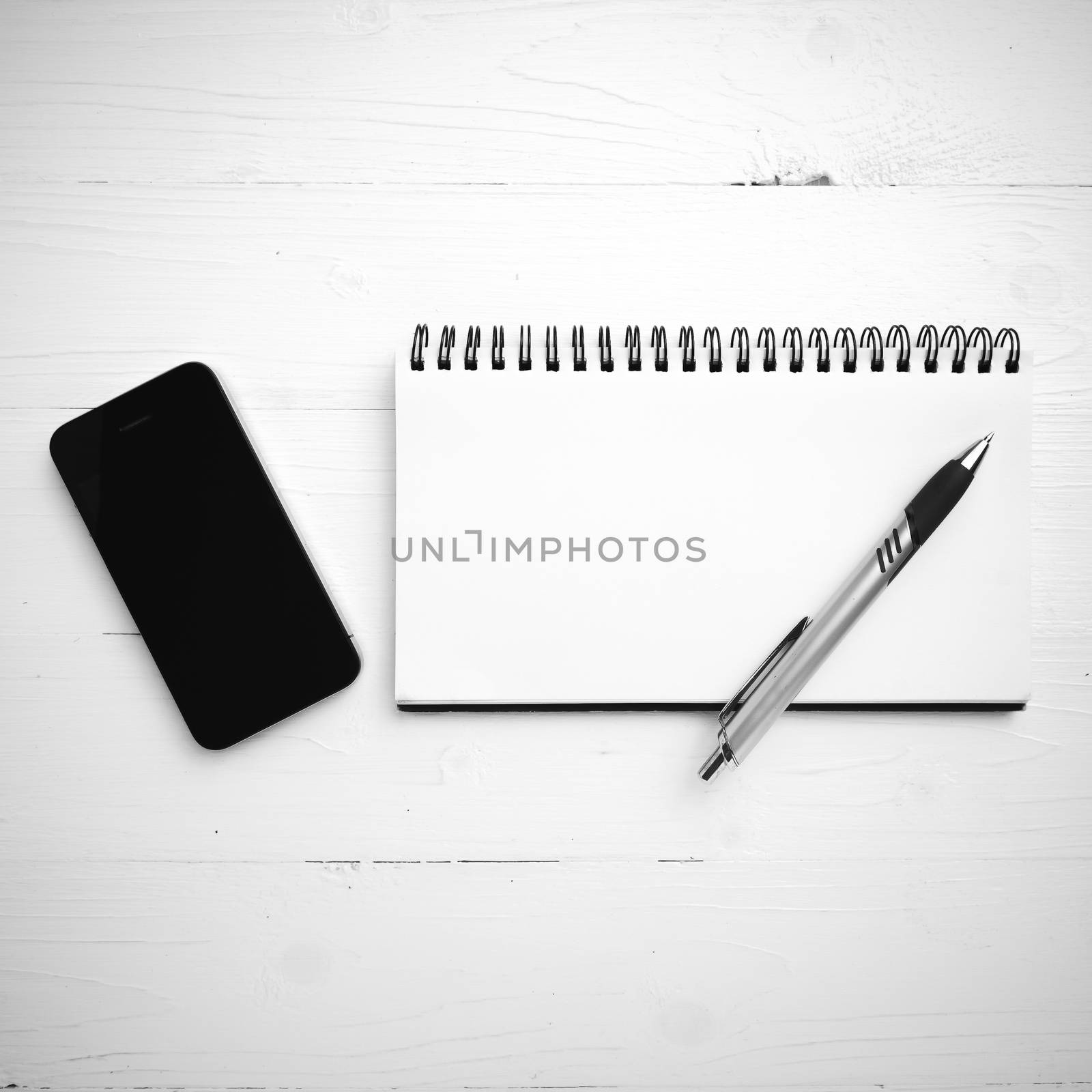 notepad and cellphone over white table black and white color tone style