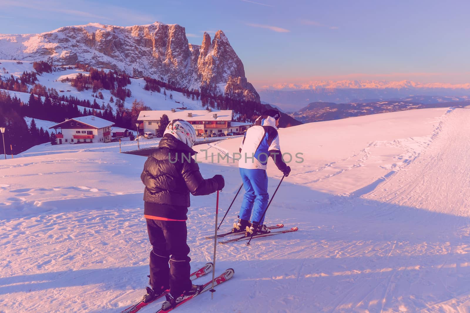 ORTISEI, ITALY - CIRCA DECEMBER 2012: Father and son skiing on the snowy slopes of the Alps.