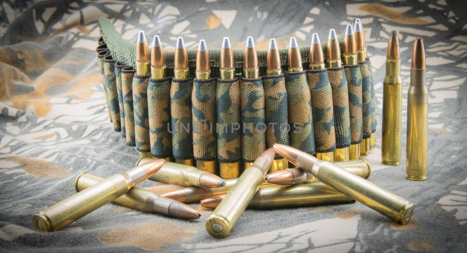 Camouflage ammunition belt for rifle on camouflage background.