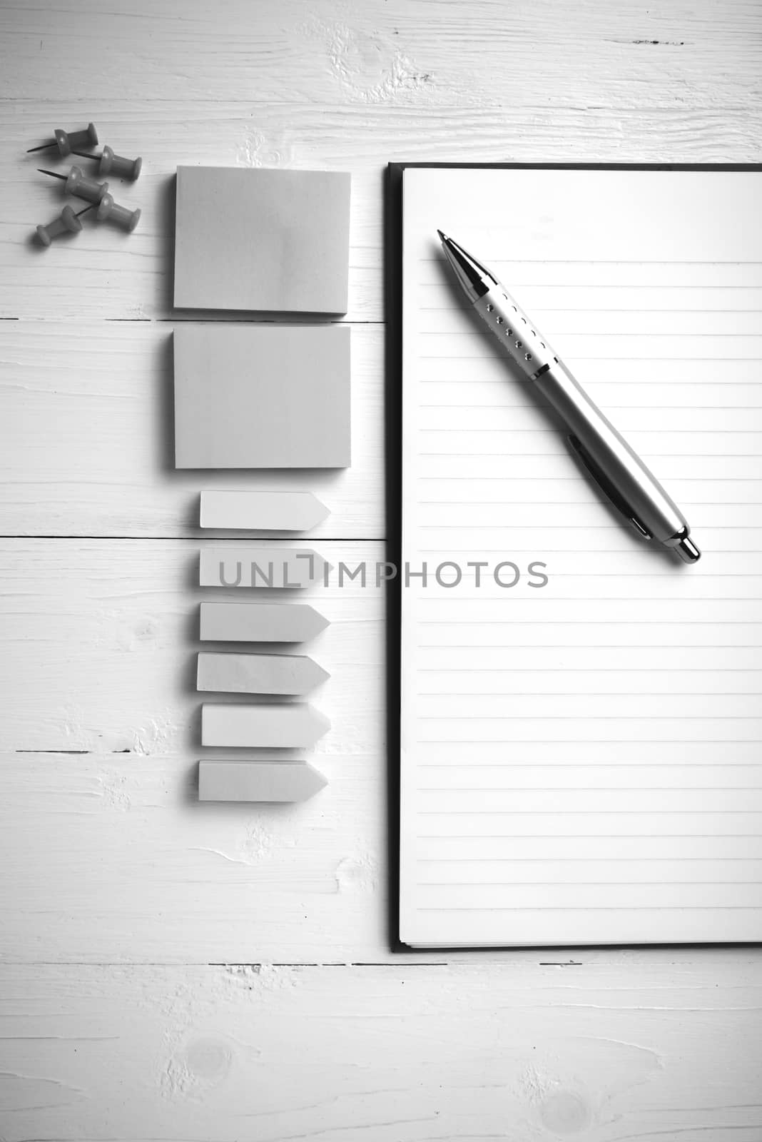 notepad with office supplies on white table view from above black and white tone color style