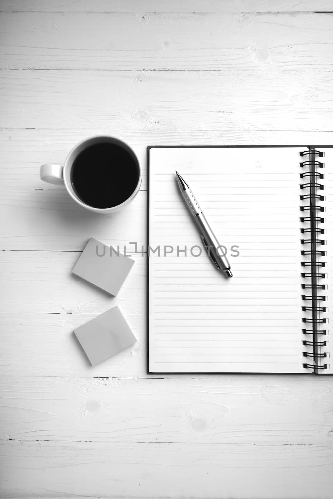 notepad and coffee cup on white table view from above black and white tone color style