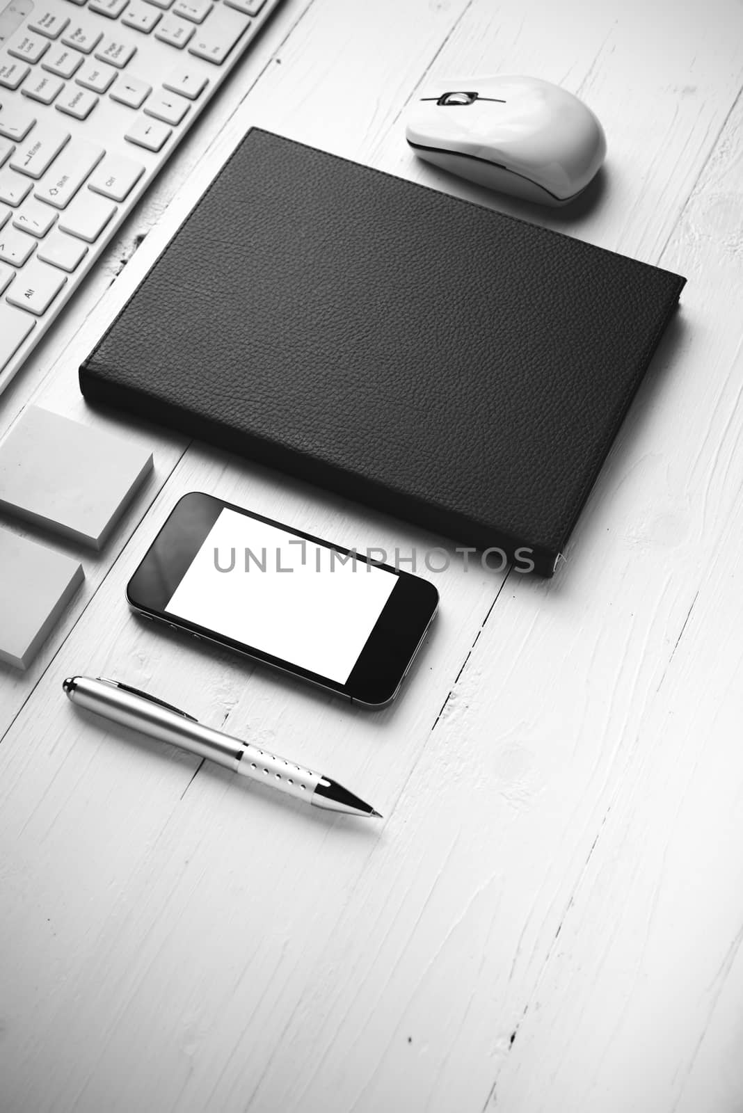 computer and brown notebook with office supplies on white table black and white style