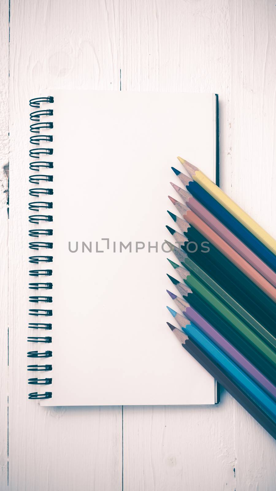 notepad with color pencil on white table view from above vintage style