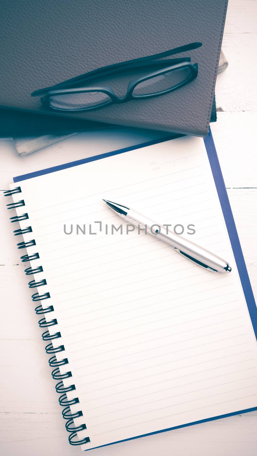 notepad with stack of book on white table view from above vintage style