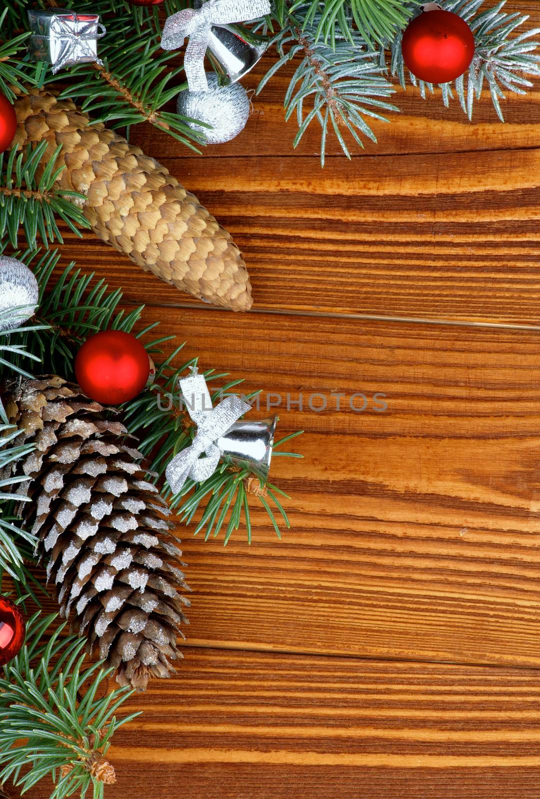 Christmas Decoration with Spruce Branches, Fir Cones with Hoarfrost, Red and Silver Baubles and Bows closeup on Textured Wooden background