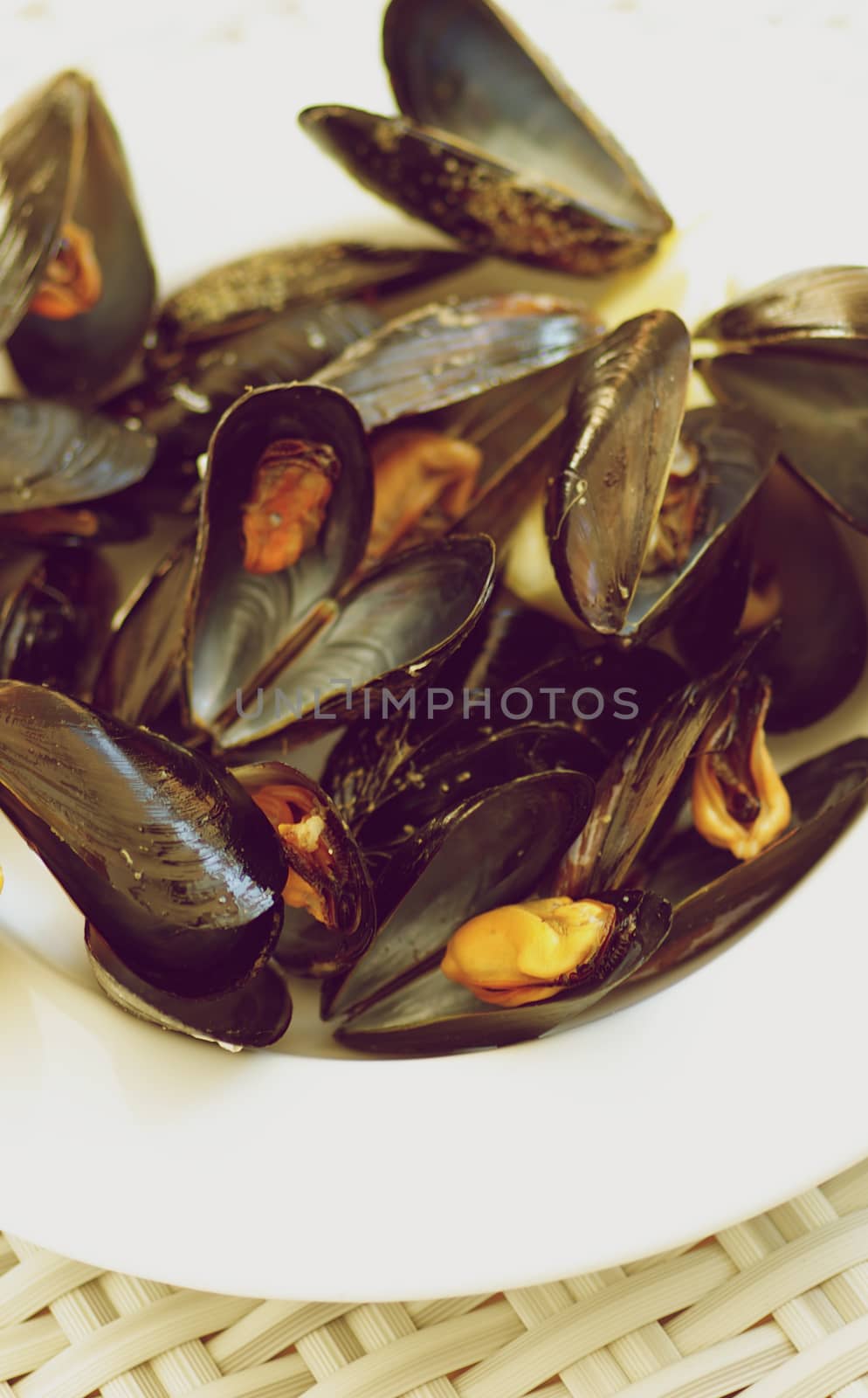 White Plate Full of Boiled Mussels closeup on Wicker background