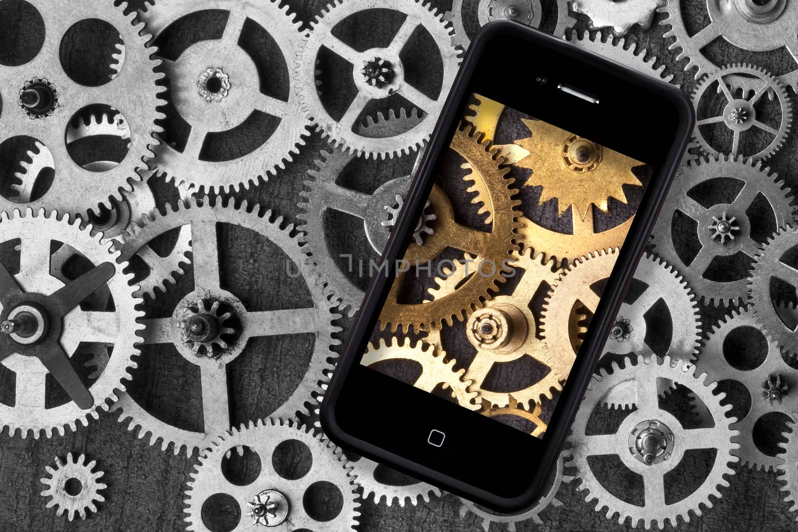 Industry - A modern digital smartphone adding color to a retro background of old clockwork cogs and gears.